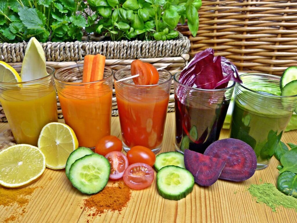 Five differently colored smoothies, yellow, orange, red, purple, and green.