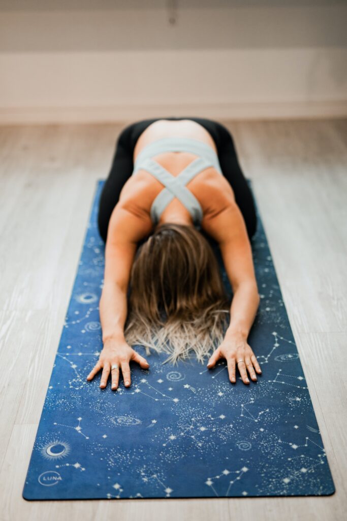 A woman is in the child yoga pose.