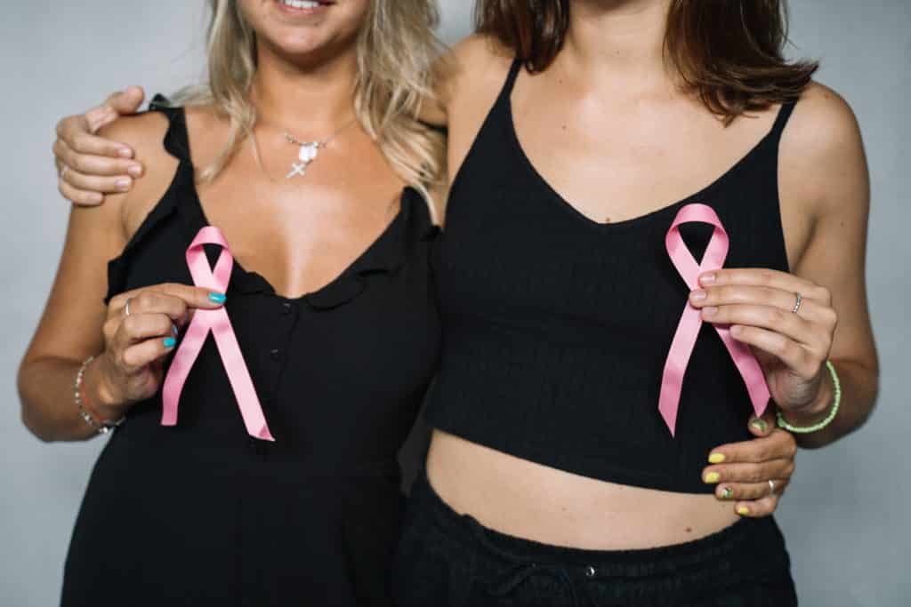 Two woman dressed in black celebrating Breast Cancer Awareness Month