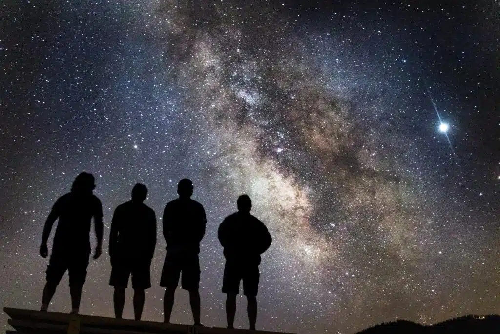 Four people staring up at stars in the night sky.