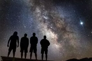 Four people staring up at stars in the night sky.