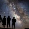 Four people staring up at stars in the night sky.