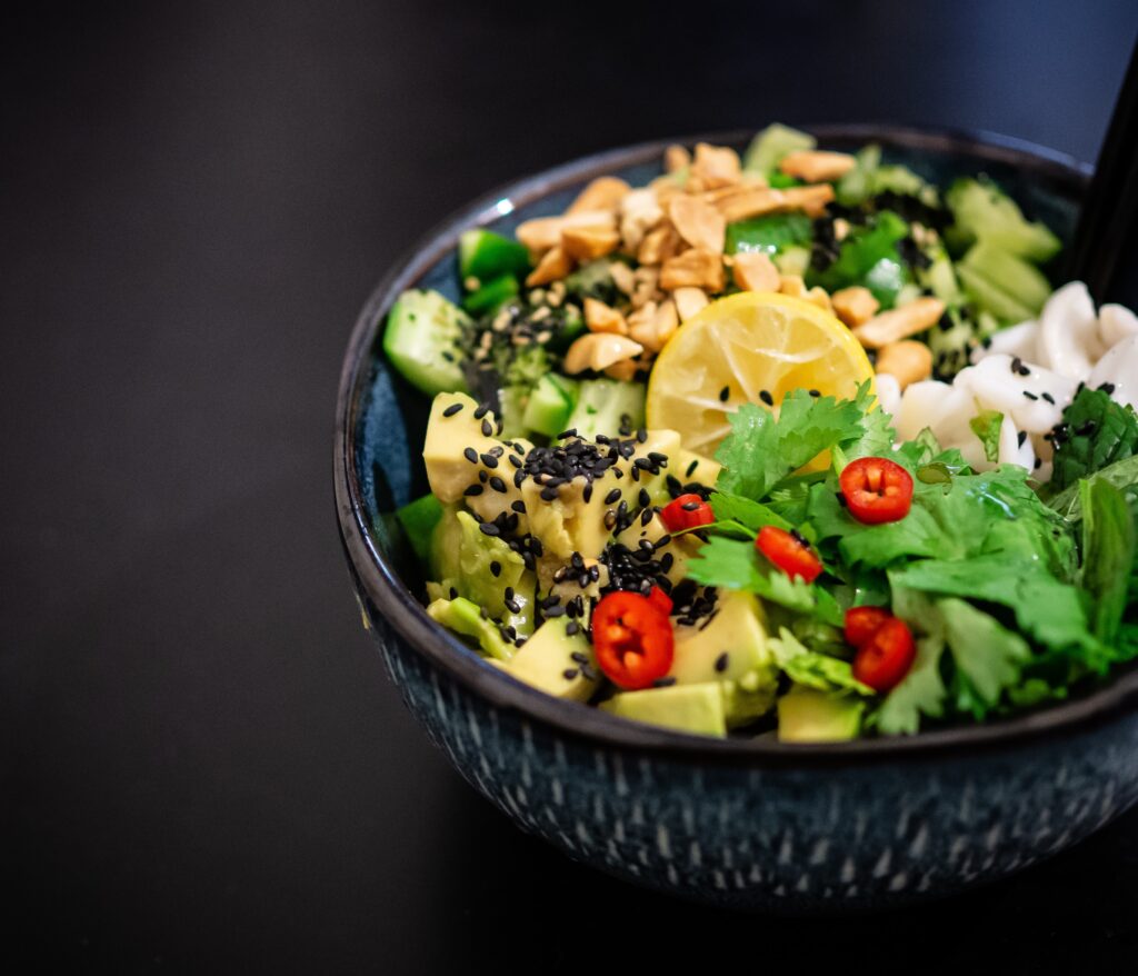 A salad with lettuce, tomatoes, cucumbers, and a slice of lemon.