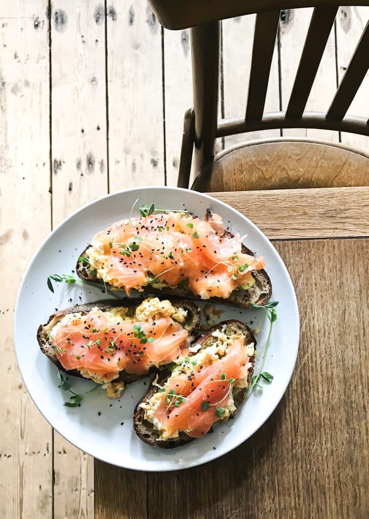 Three portions of salmon topped with herbs and spices.