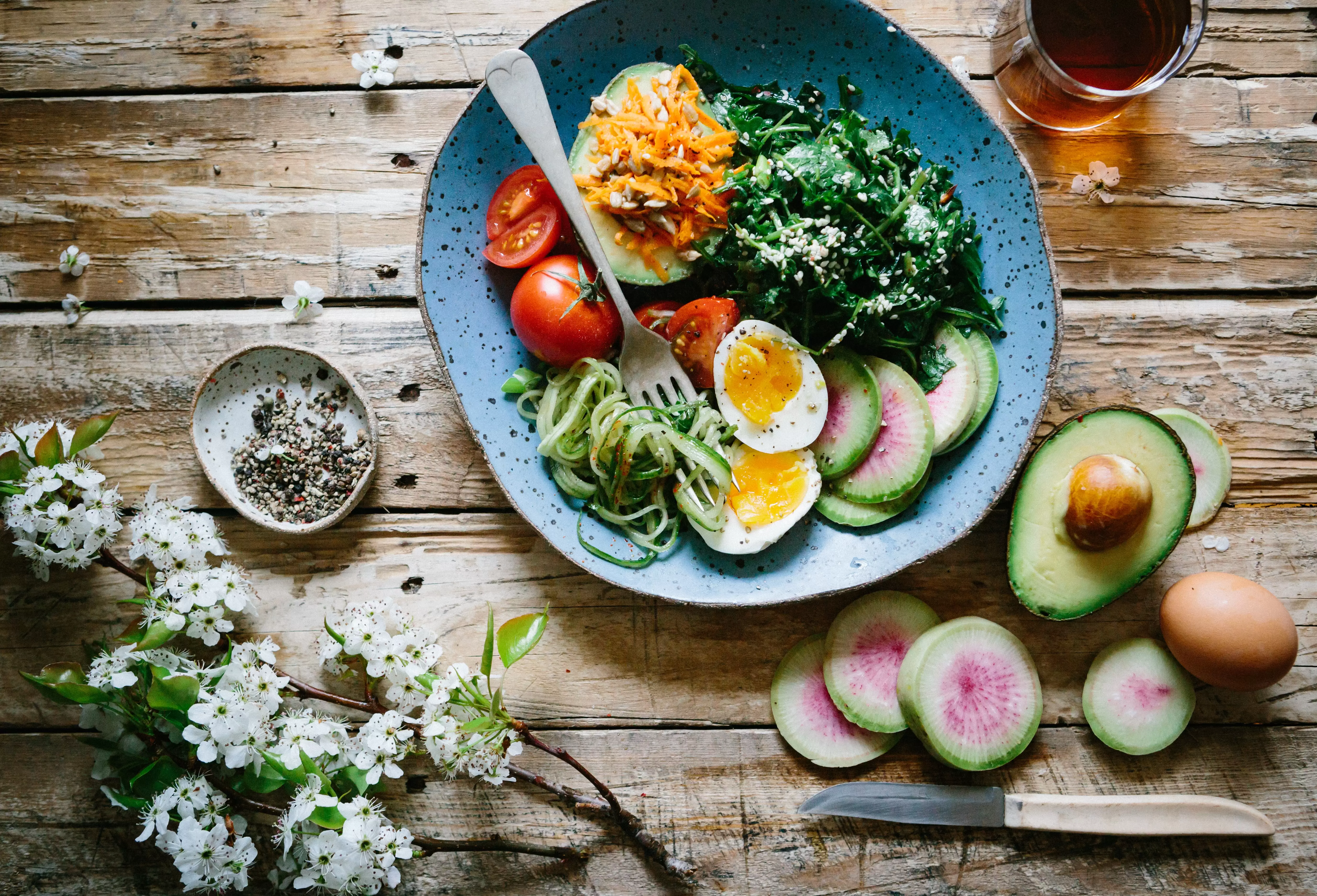 a bowl of sliced boiled eggs, tomatoes, spinach with a serving fork