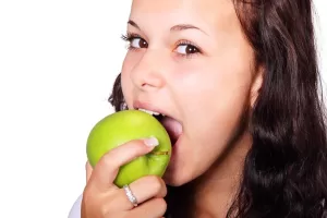Girl biting an green apple.