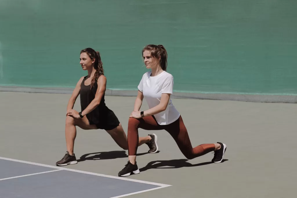 Two woman doing lunge exercise.