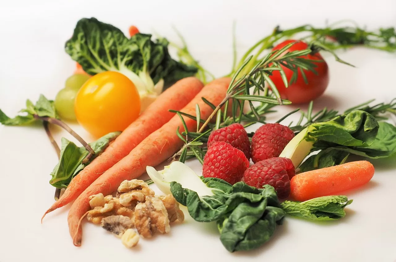 Carrots, strawberries, a tomato, yellow pepper, and green leaf's of lettuce.