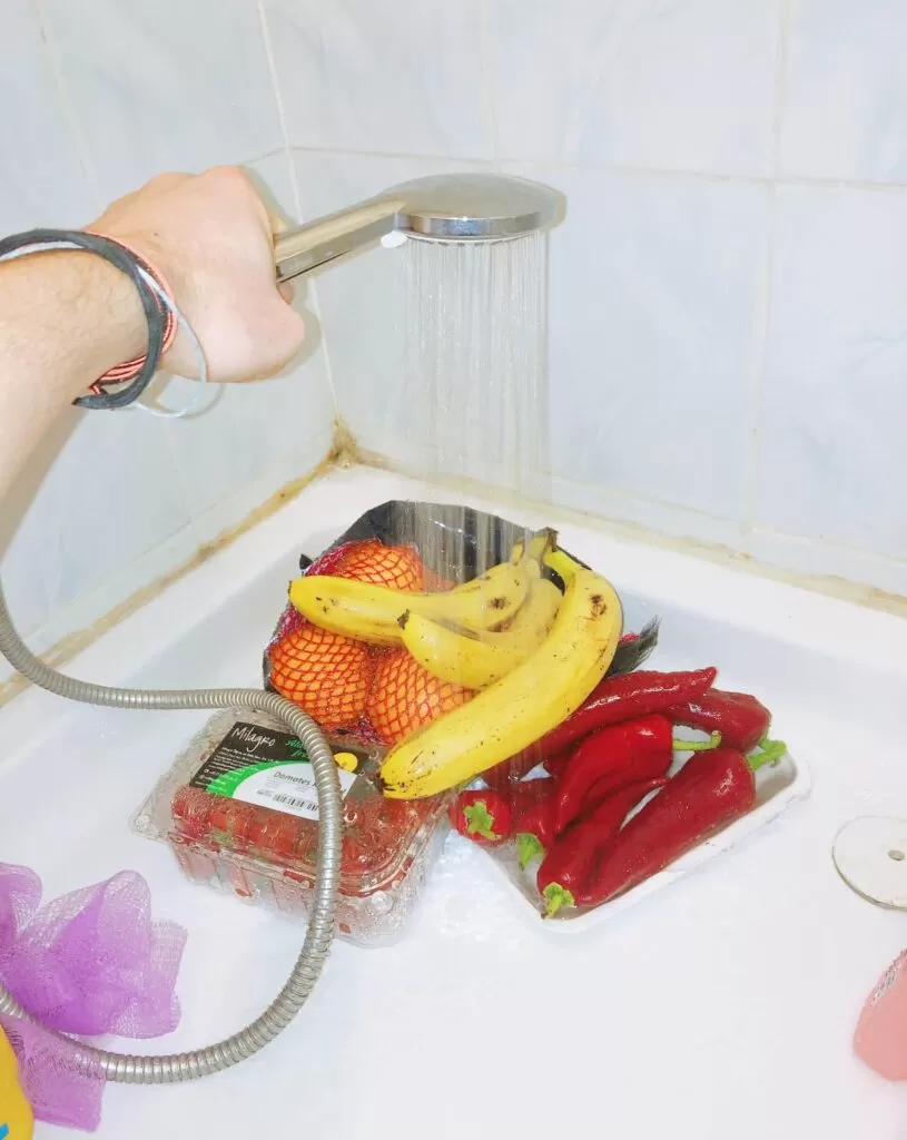 Washing bananas, oranges, and red chili peppers.