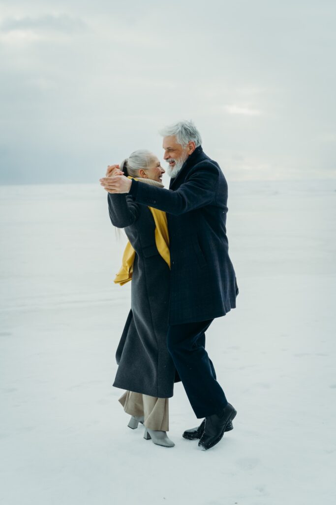 A man and a woman wearing all black in an embrace dancing.