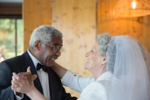 A man in a tuxedo and a woman in a wedding gown dancing at their wedding. 