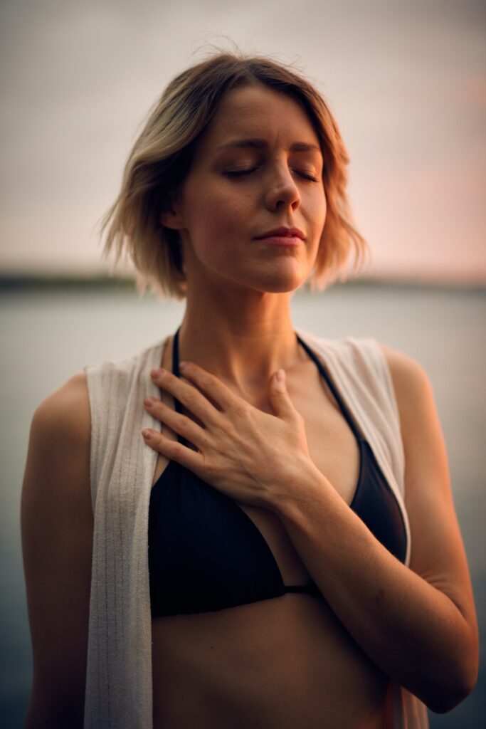 A woman with her eyes closed with her left hand over her heart.