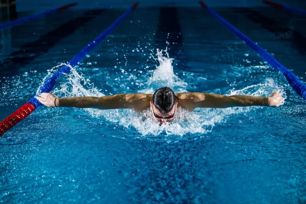 A swimmer doing the breast stroke in a inside pool.