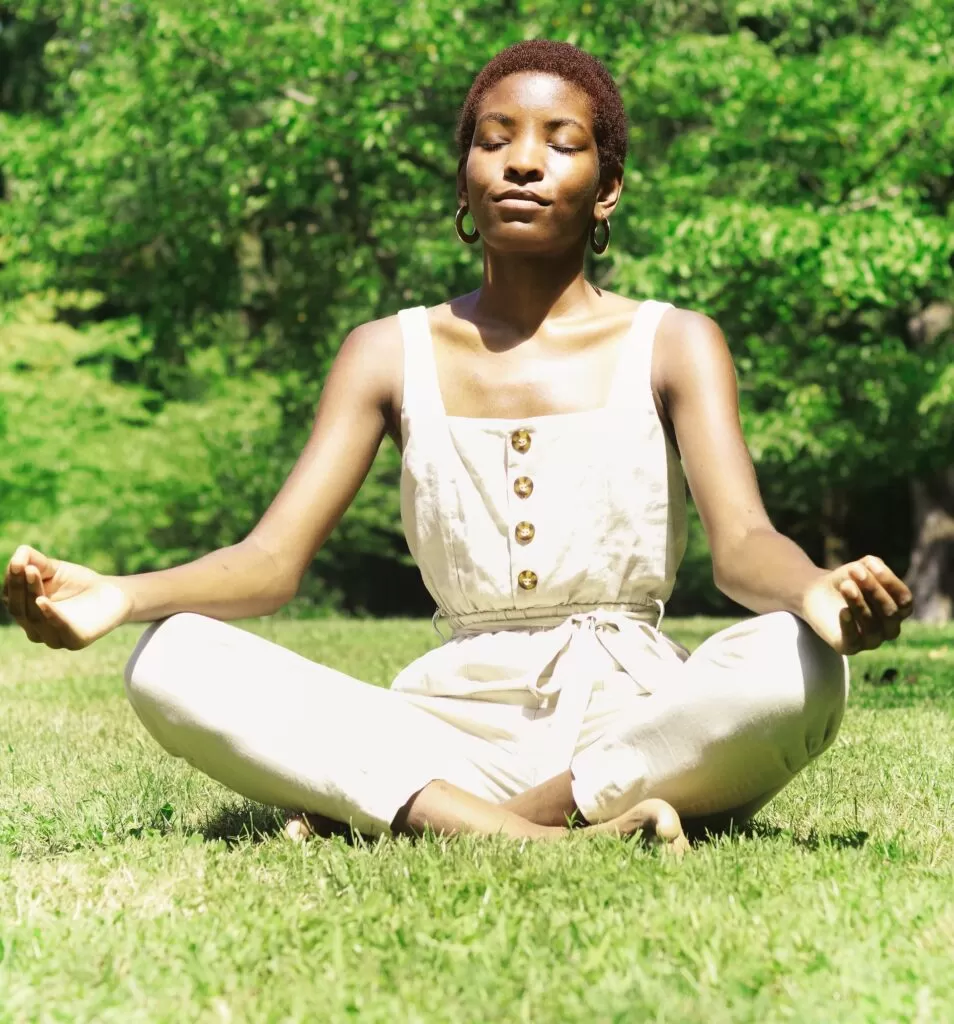 A woman outside in the sunshine meditating.