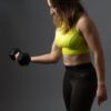 A woman doing a right arm curl with a small dumbbell.