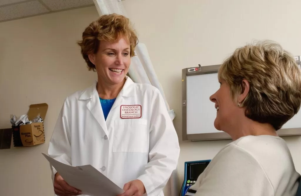 Female doctor wearing a white coat talking to a female patient.