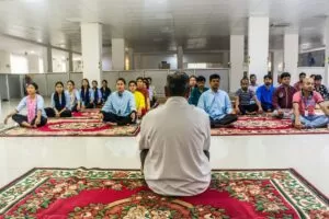 A man sitting in front of a meditating class.