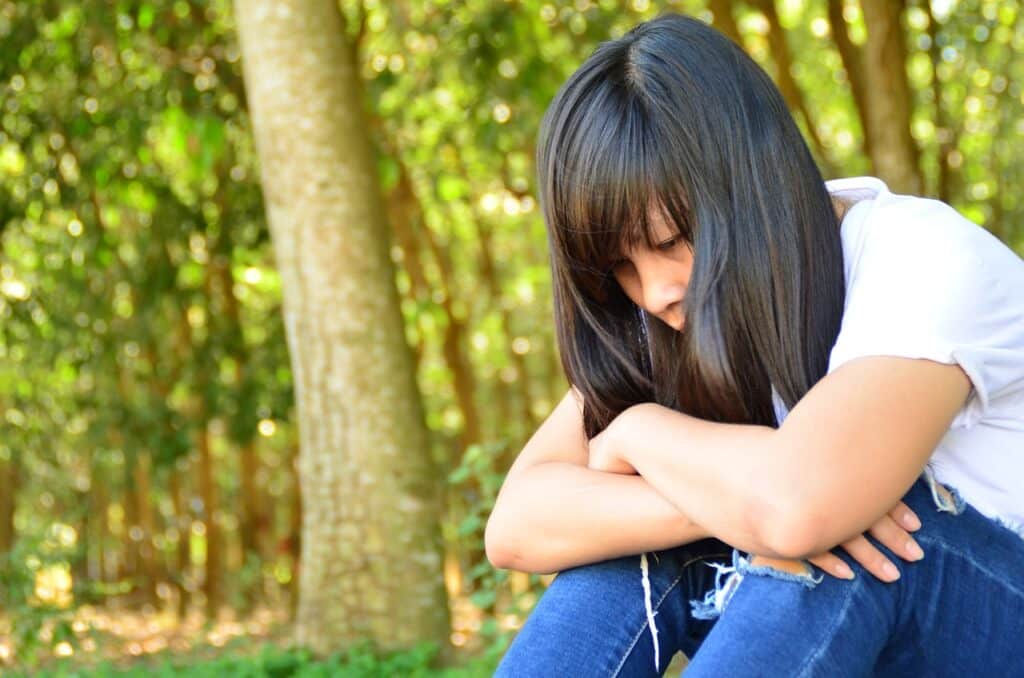 A sad girl, thinking with her arms folded across her knees.