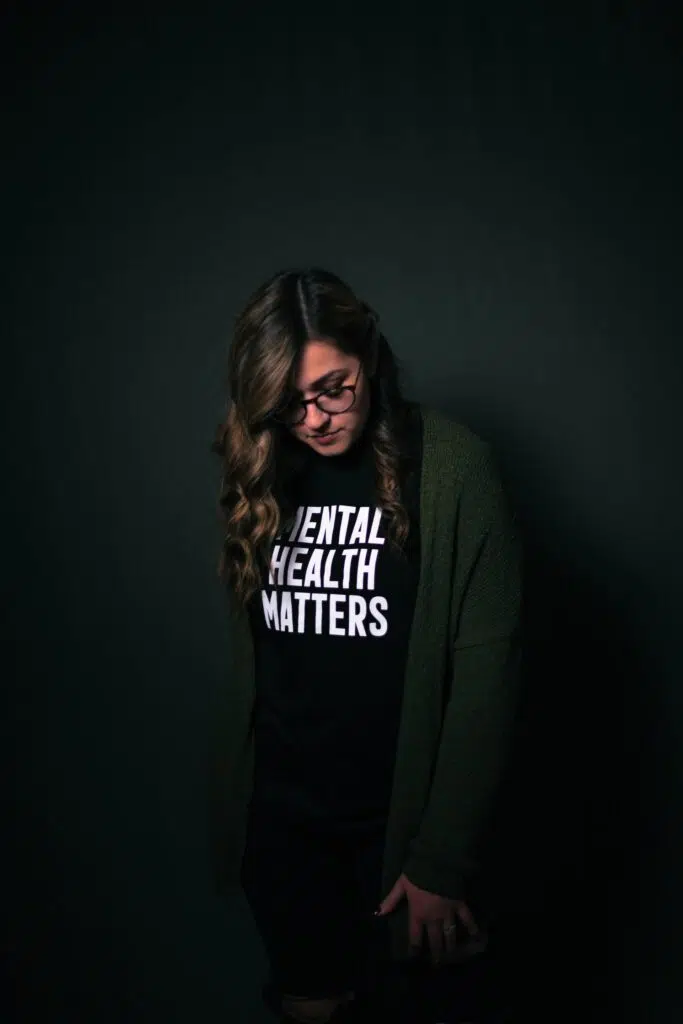 A woman wearing a black tee shirt with the words mental health matters on the front of it.