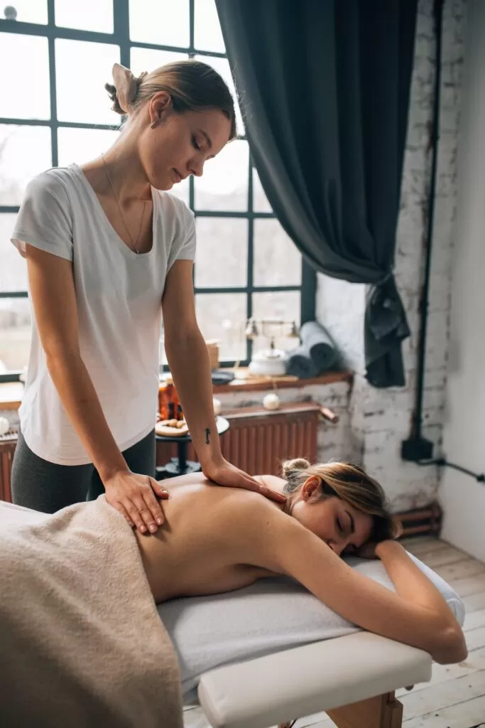 A woman laying on her stomach getting a back massage from a female masseuse.