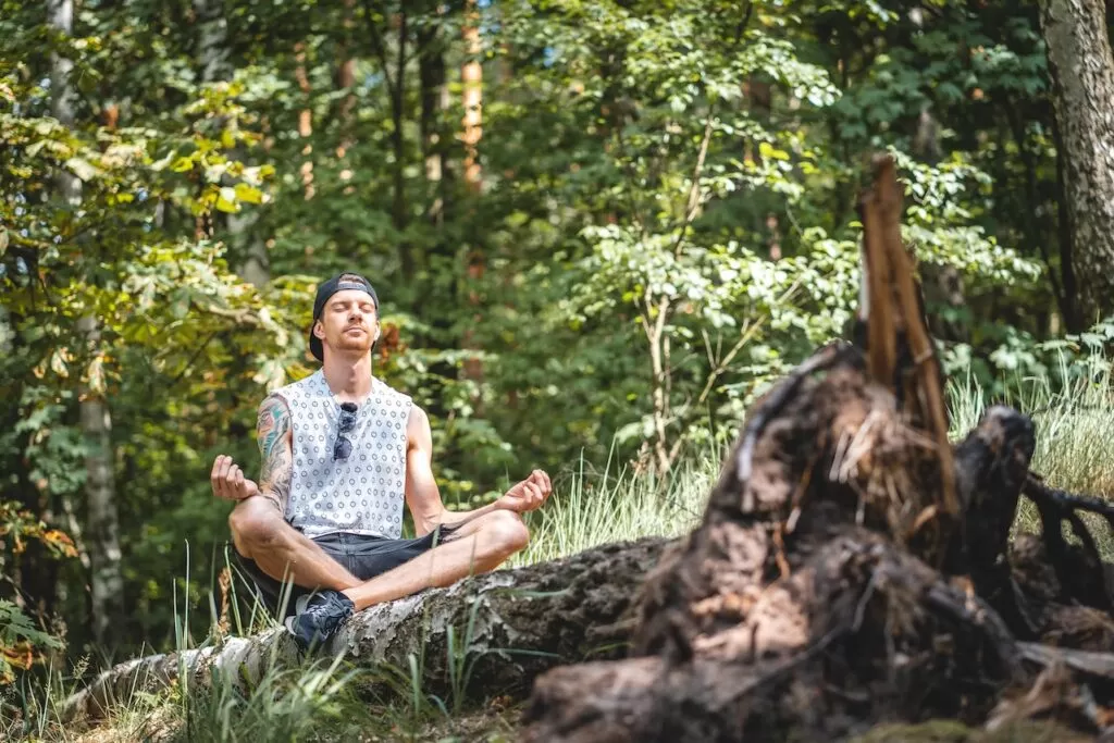 A young man meditating outdoors.