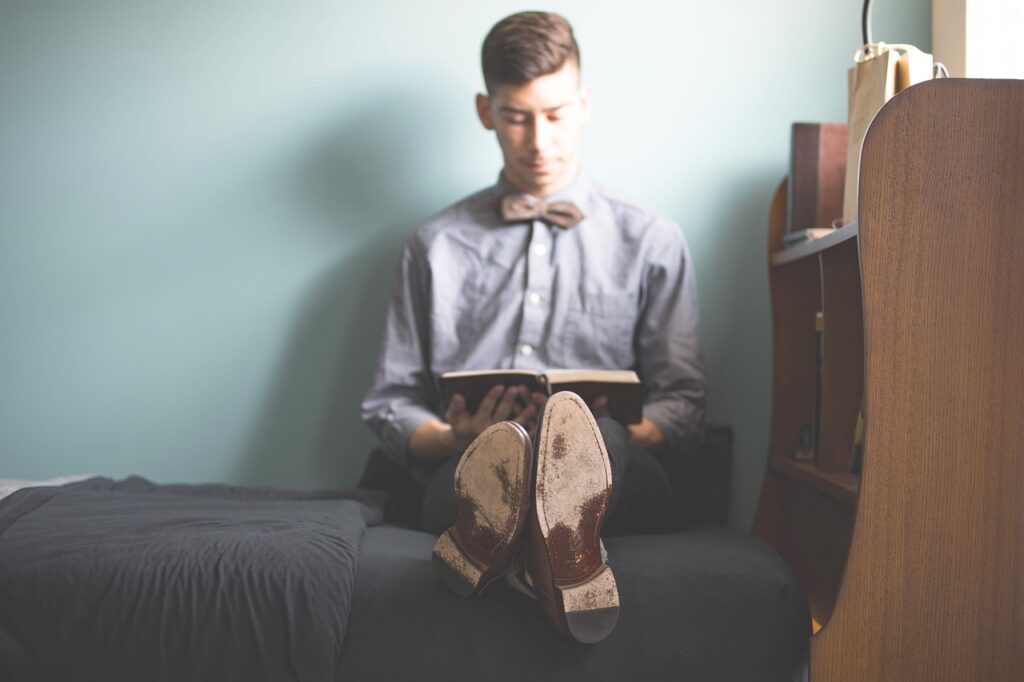 A man sitting on a bed reading a health and wellness book.