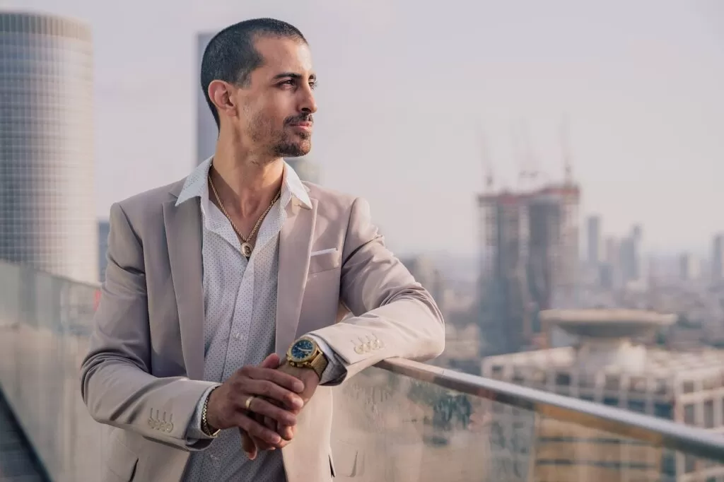 A male model standing on the balcony watching the city.