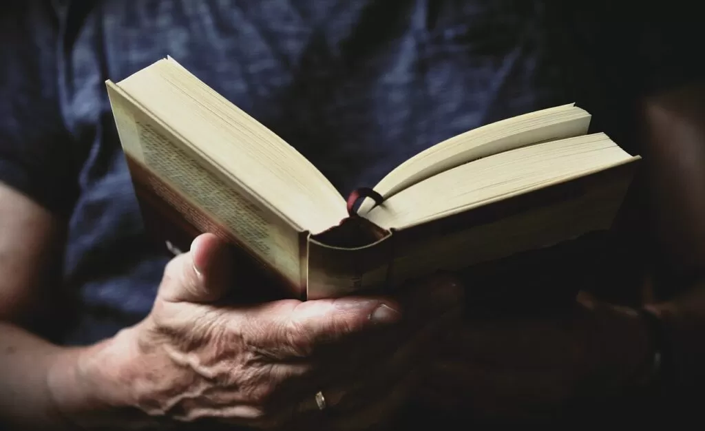 An open book being read held by hands.