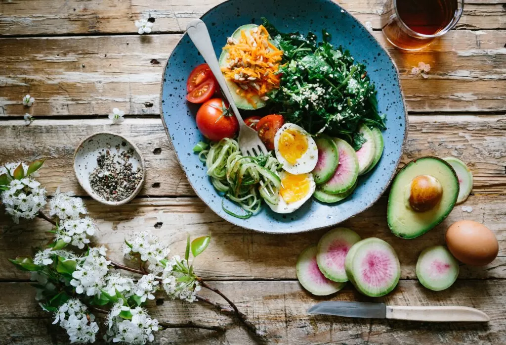 A plate with sliced boiled eggs, sliced avocados and cherry tomatoes.