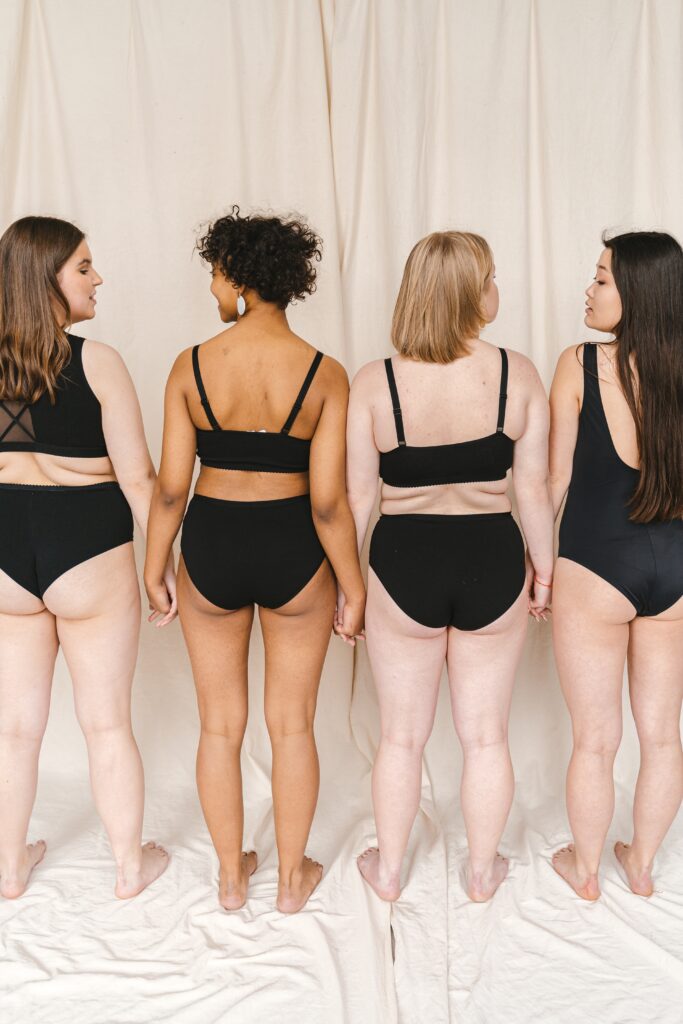 Four women dressed in black underwear with their backs turned toward us.