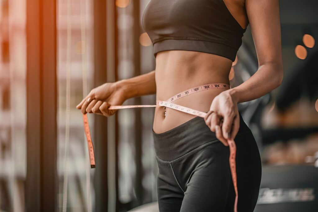 A woman measures her waist and her weight loss.