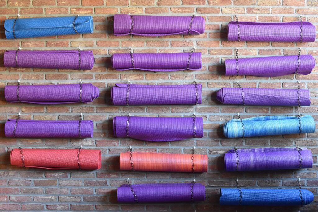 Yoga mats in an assortment of different colors rolled up and hanging on a wall.