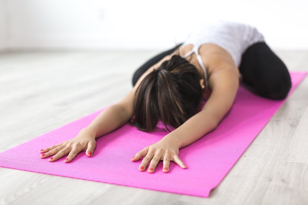 a woman stretching on a pink yoga mat