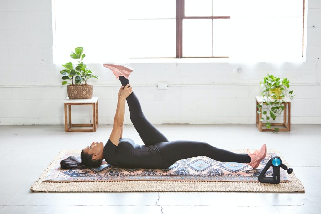 woman in black tank top and black leggings lying on black and white floral area rug