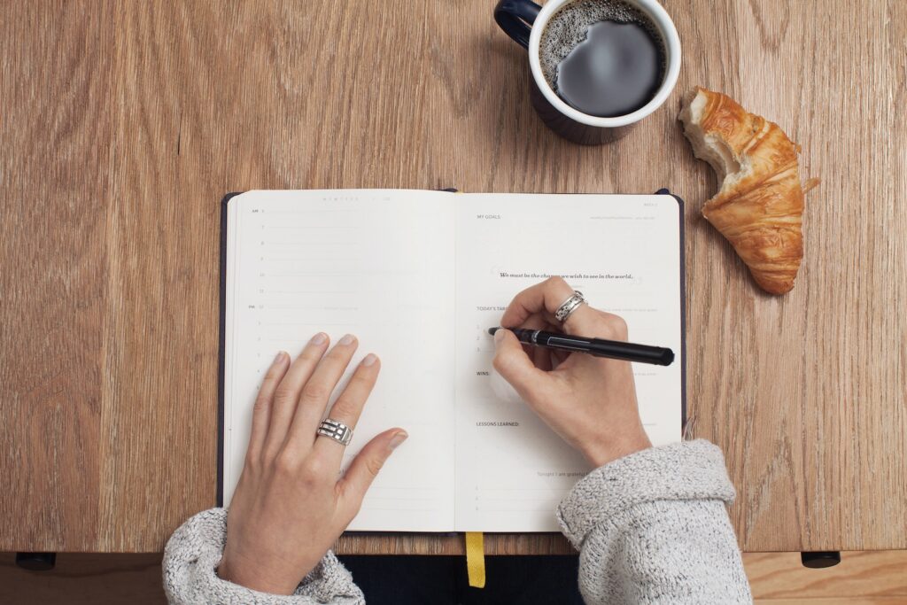 person writing in a book doing diet planning