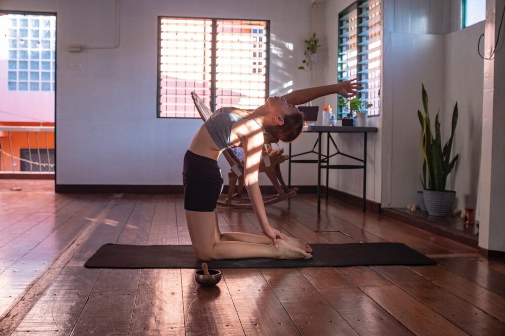 A woman in black shorts and white tank top doing morning exercise with yoga