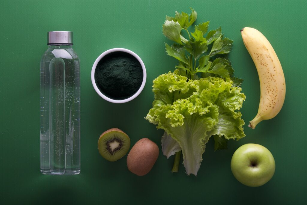 assorted fruits and vegetables and bottled water on a green surface