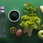 assorted fruits and vegetables and bottled water on a green surface