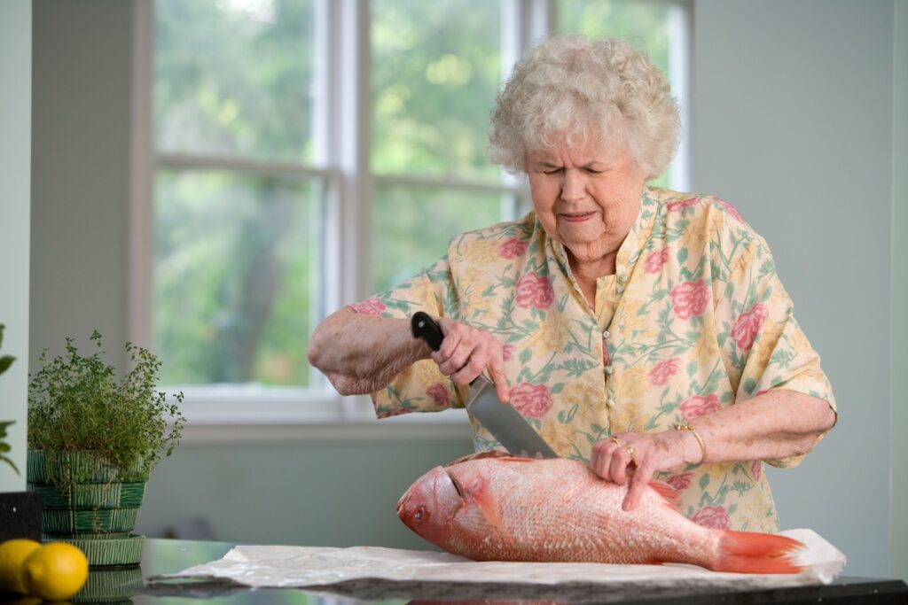 woman in yellow and pink floral blouse overcoming challenges of cleaning fresh fish