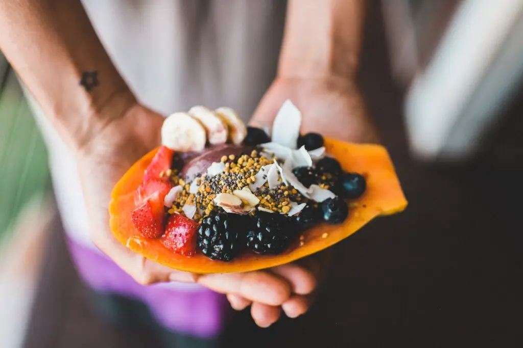 Person holding blue berry with strawberry dessert that will help with weight management.