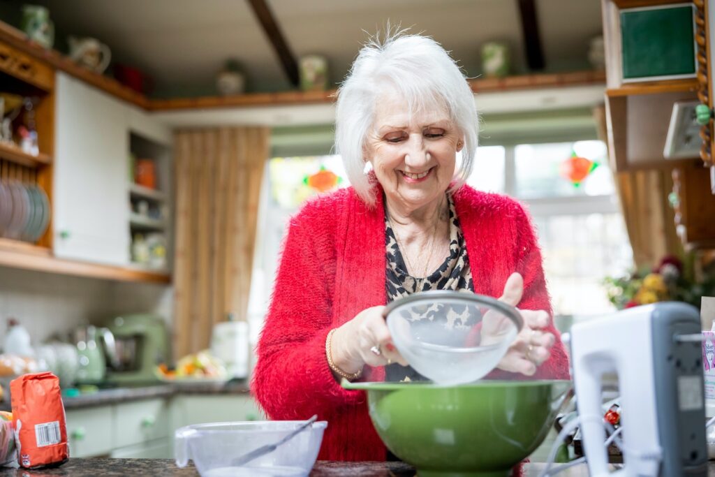 a woman wearing a red sweater using a mixing bowl in a kitchen