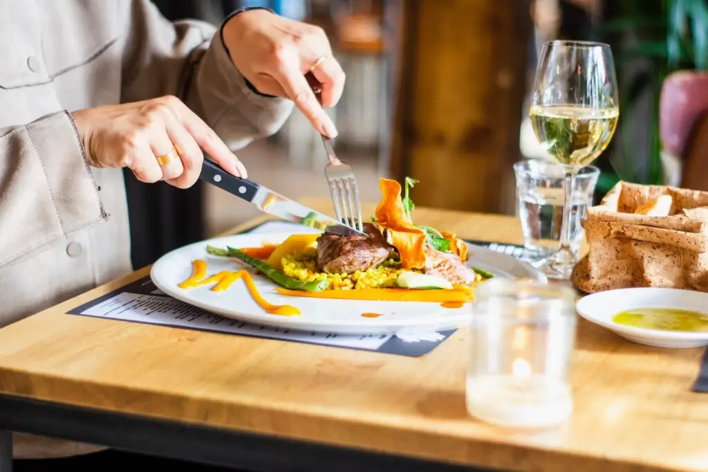 person healthy eating for seniors with a knife and fork from a white plate of food