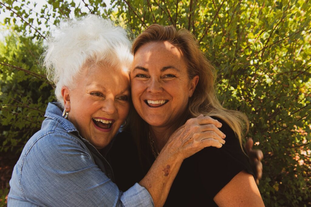 two woman a mother and daughter, hugging and smiling, wearing