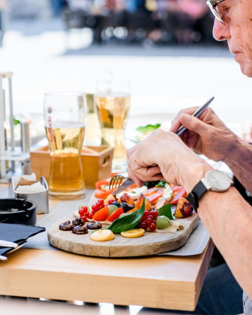 man slicing fruits while eating at the dinner table wearing a watch